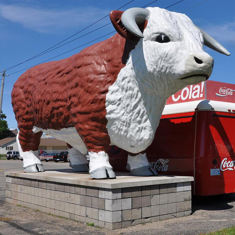 Jättiläinen lasikuitukukkalehmäveistos